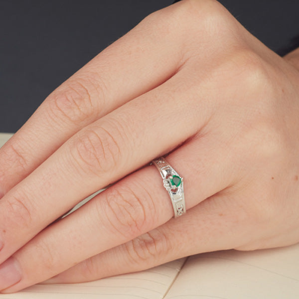 9ct white gold wishbone claddagh ring with heart shaped emerald in the middle as shown on a ladies finger