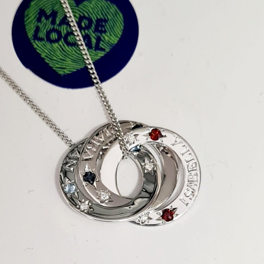 9ct white gold tripple ring pendant and chain.  The pendant consists of 3 interlocking flat circles.  Each circle represents the clients children.  We have engraved each circle with the name, we also set the childs birthstone into each of the circles.