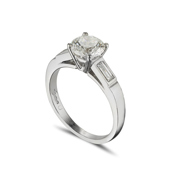 Platinum solitaire engagement ring with baguette diamonds set in the soulders on a chunky band