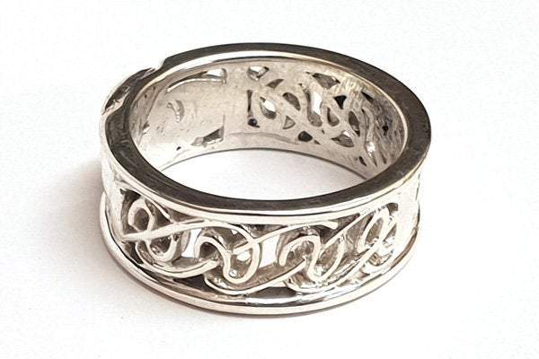 sterling silver 8mm wide calddagh band, there is a claddagh symbol in the centre of the ring with a pierced celtic design going around the ring, from the back view