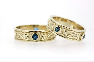 yellow gold celtic design matching his and hers rings, they are set with 3 sapphires in each ring, the 3 stones are rubover or bezel set at north east and west points of the ring